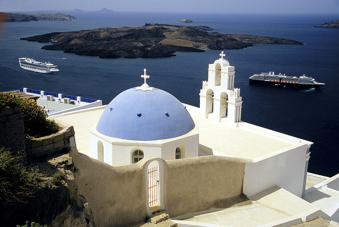 Dome and bell tower of Kimis Theotokov Greek Orthodox church at Thíra with cruise chips anchored below. Santorini, Cyclades Islands. Greece