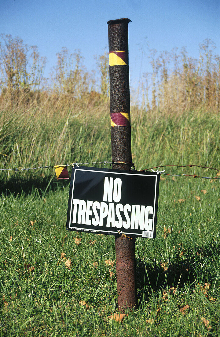 No trespassing sign in field near weeds, Indiana, USA