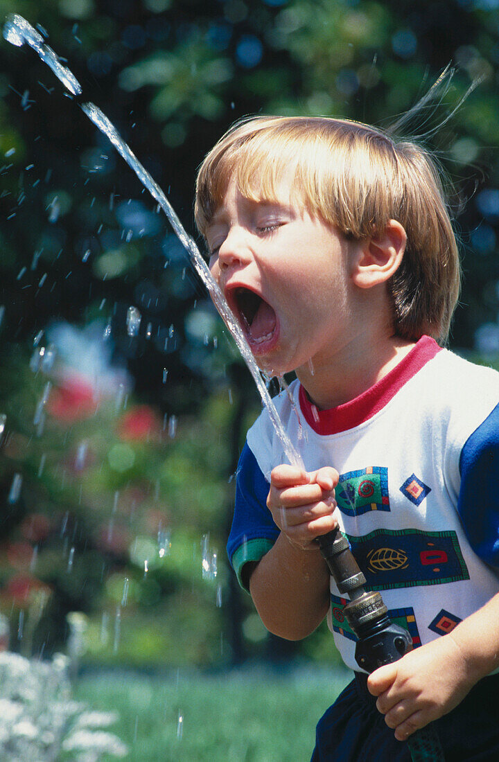 Boy drinking from hose