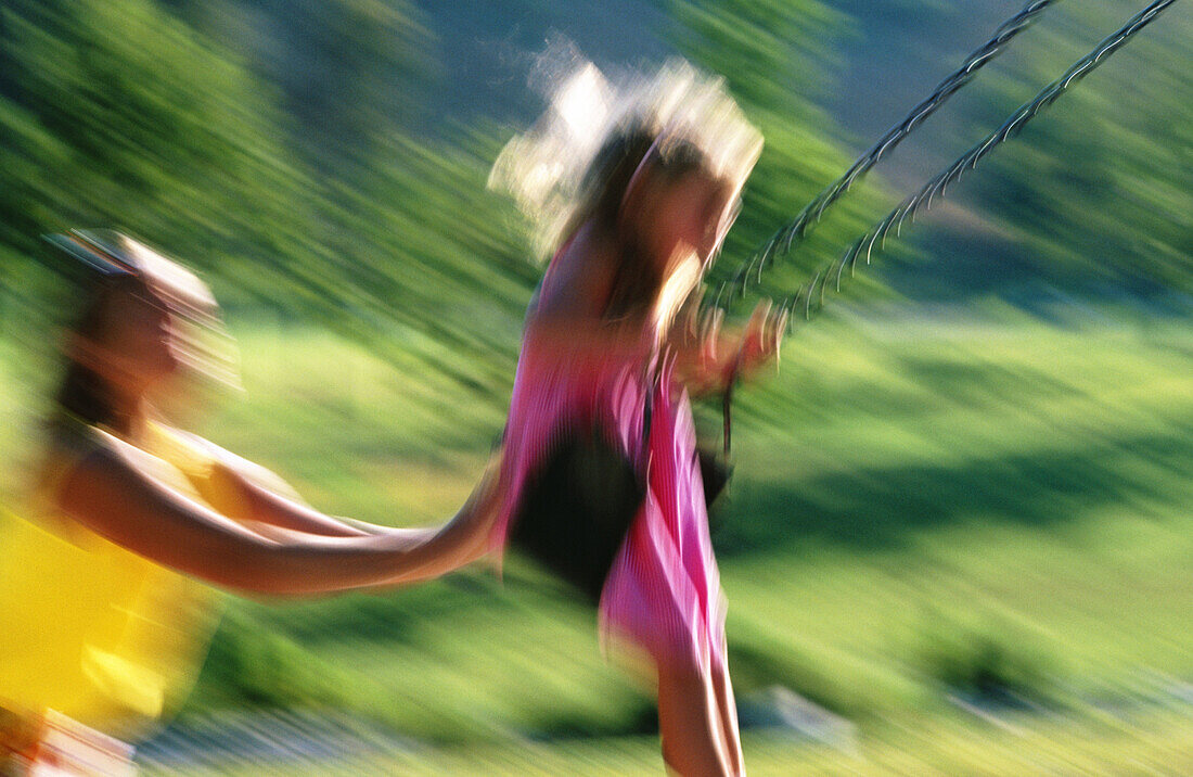Mother pushing daughter on the swing