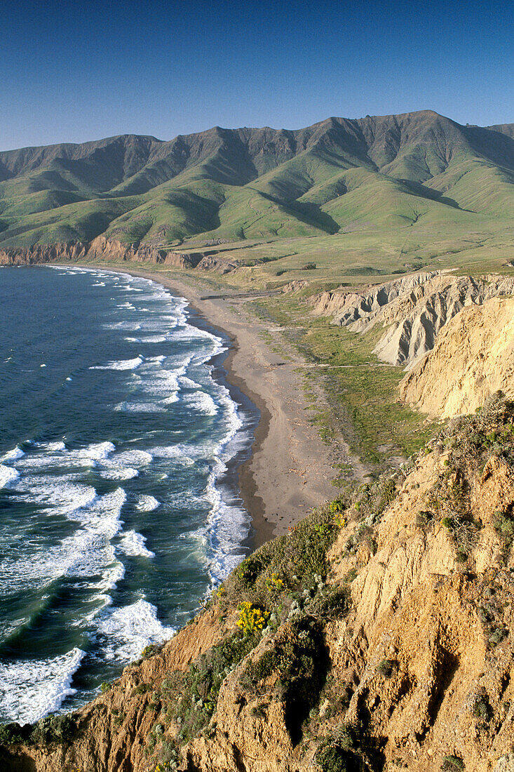 Green hills in spring and coastal waves breaking on sand shore of Christy Beach. Santa Cruz Island. Channel Islands Natinal Park. California. USA
