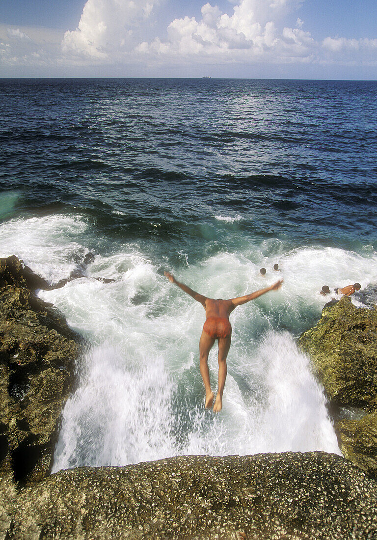 Boy jumping into sea from Malecon wall. Havana. Cuba