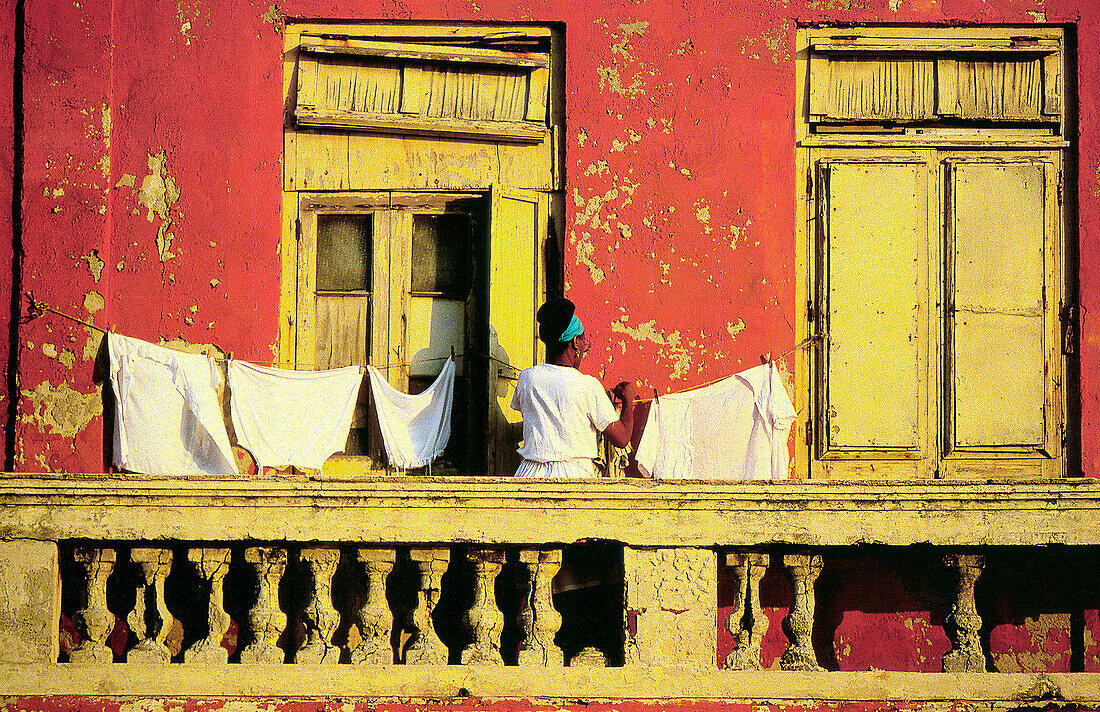 Woman hanging laundry on balcony of old building. Havana. Cuba