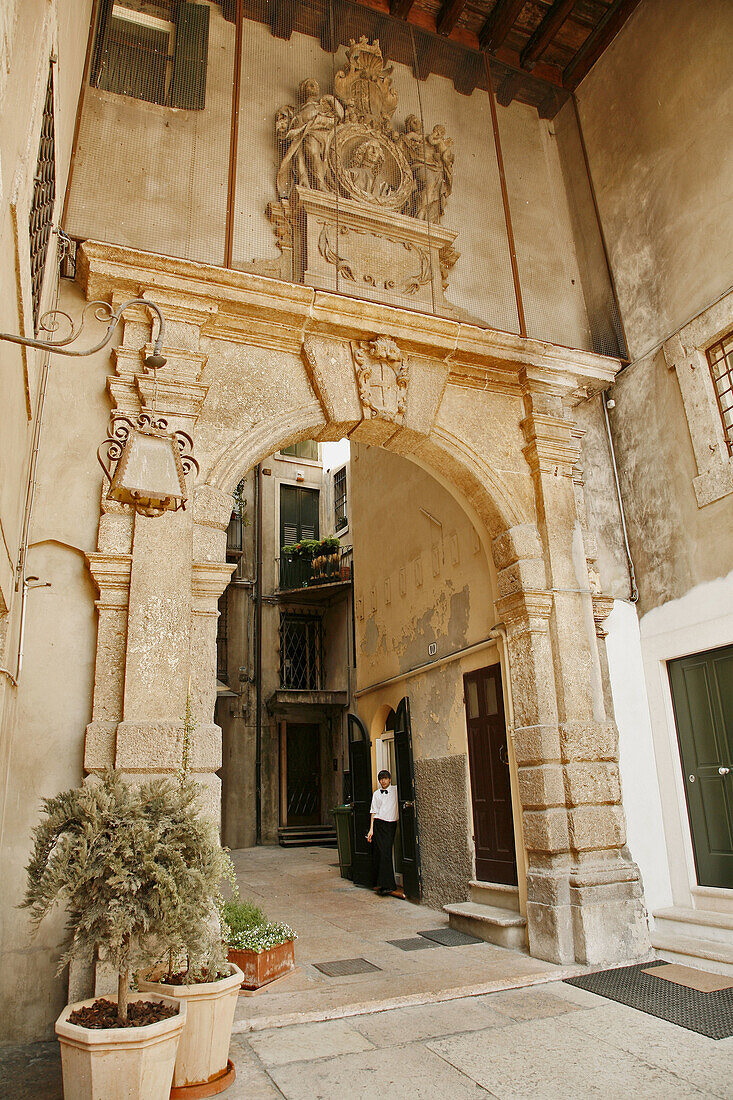 young man (waiter) smoking in doorway in courtyard, Verona, Italy