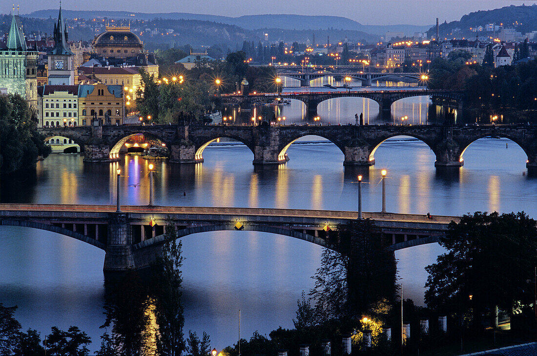Charles Bridge (Karluv Most), Prague s most famous, was built in 1357 by Emperor Charles IV on the site of an older bridge. On the left are (L. to R.) the Old Town Bridge Tower, Old Town Water Tower, and National Theater. Dusk. Prague. Czech Republic