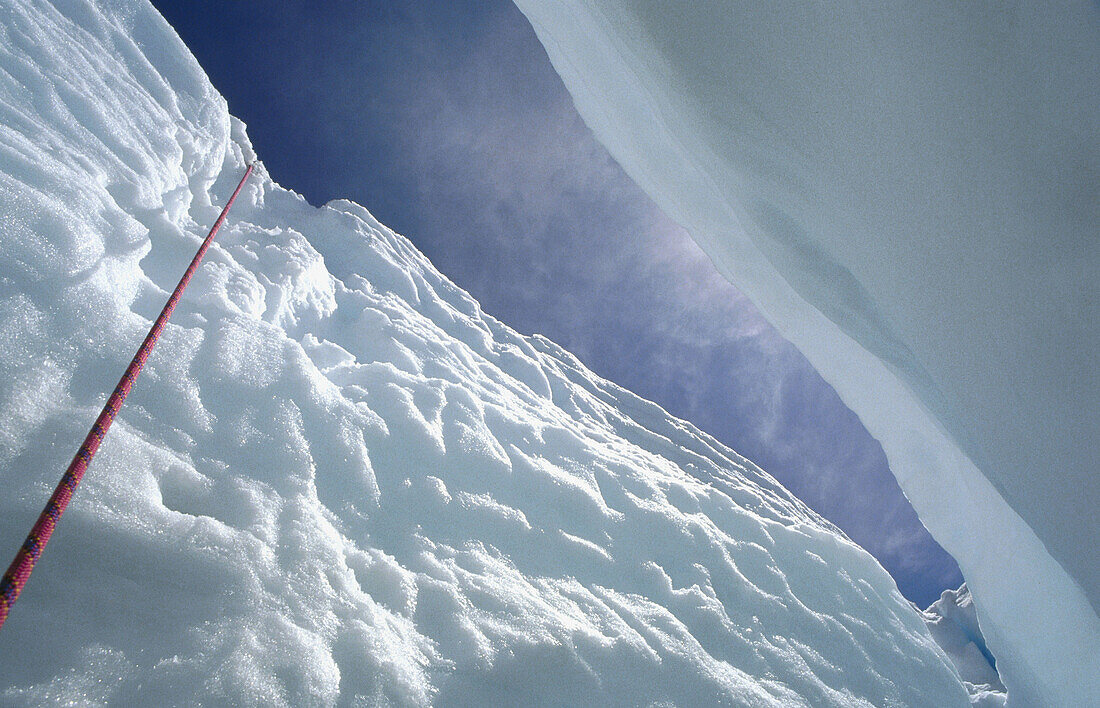 Climbing rope descends into crevasse on Easton Glacier. Mount Baker. Washington. USA