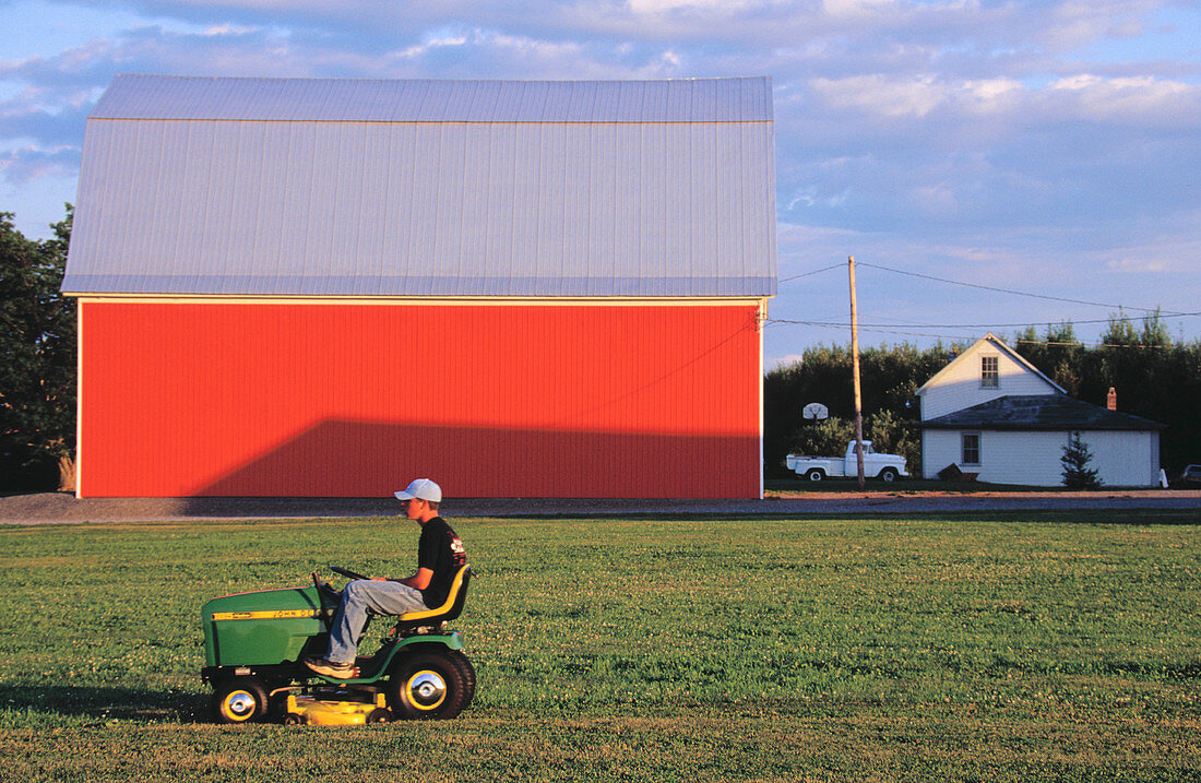 Farmboy on riding lawn mower. Aroostook County. Maine. USA