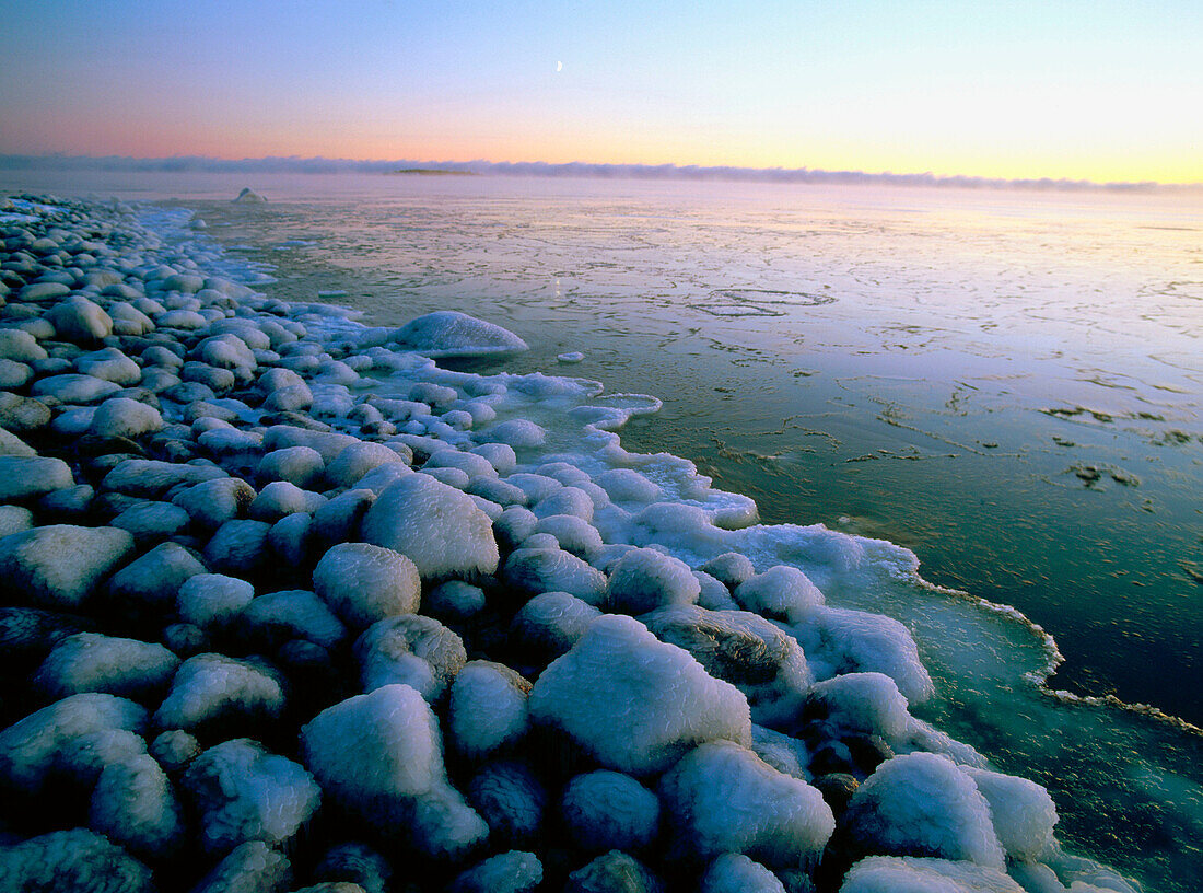 Icy stones on the shore under the evening light of Langnasudden. Vasterbotten. Sweden