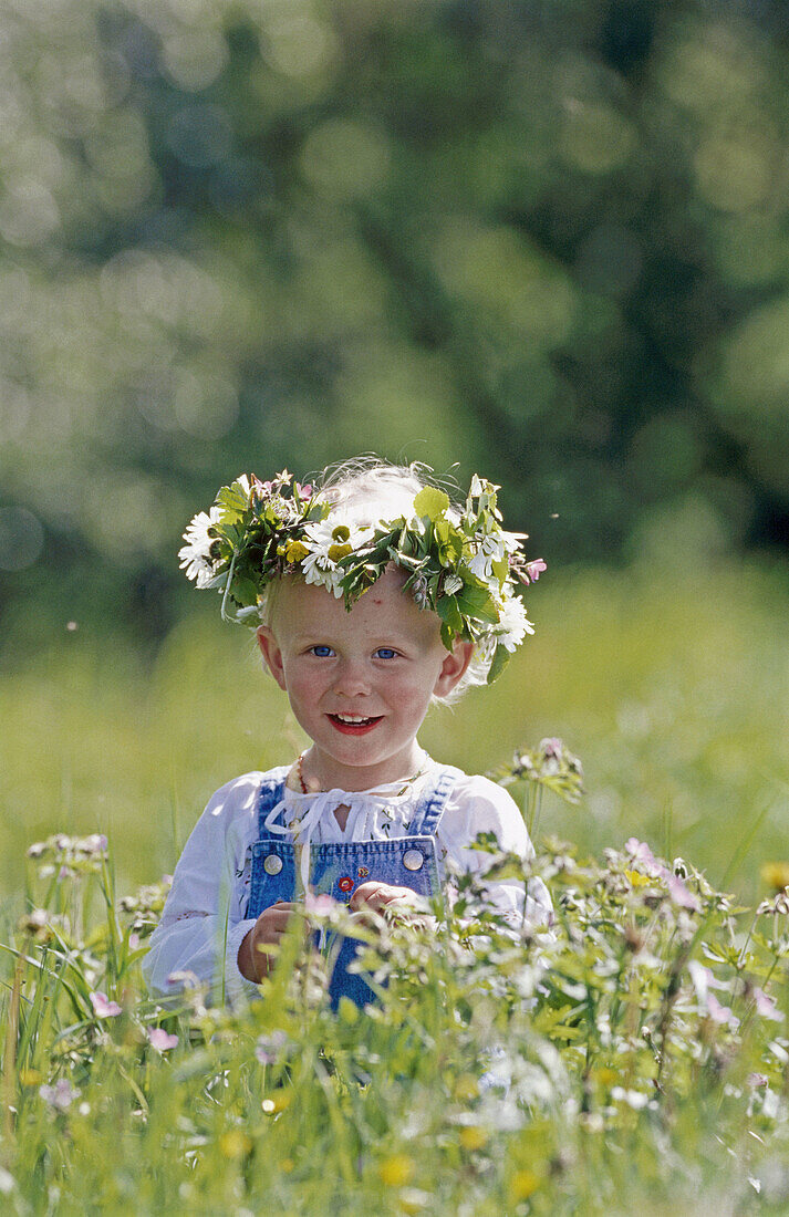 Two year old girl with wreath made of flowers in direct light. Västerbotten, Sweden