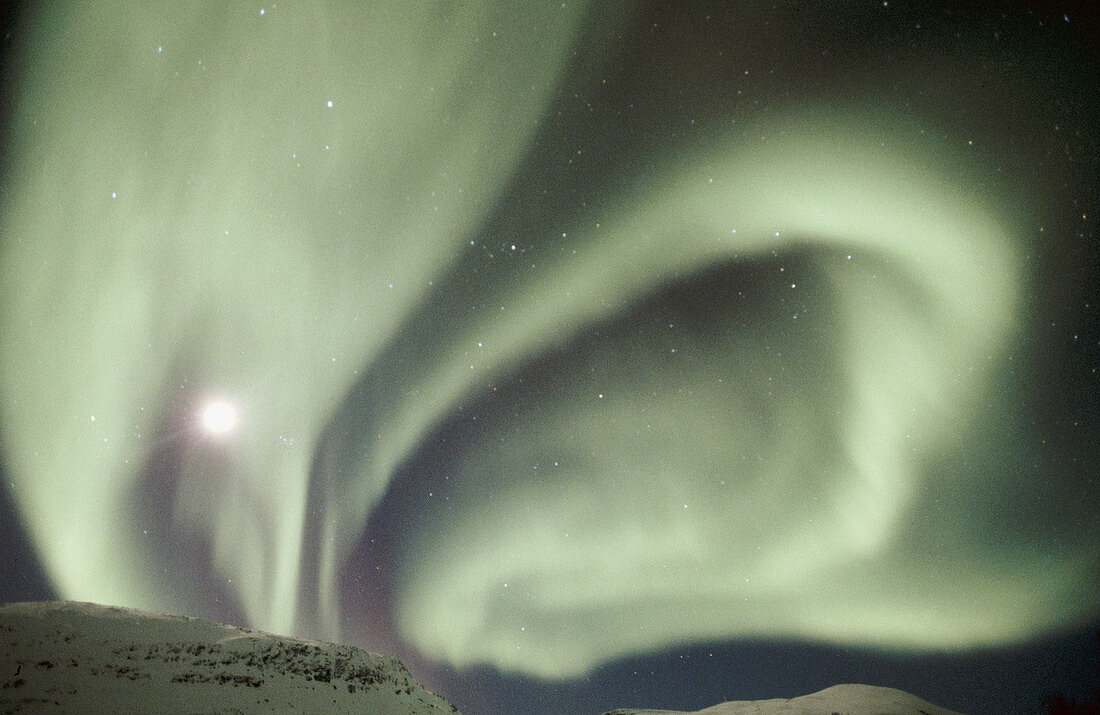 Northern lights (Aurora borealis) and full moon. Over the mountains. Bardu. Norway.