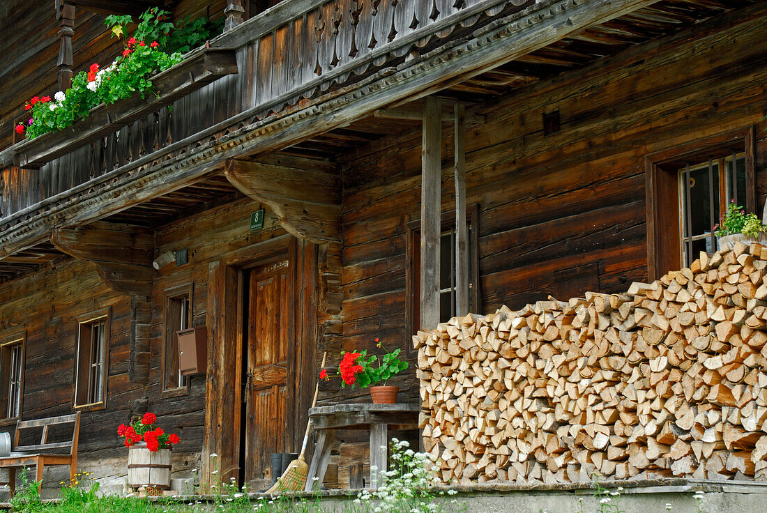 Traditioneller Bauernhof mit Blumenschmuck und Brennholzstapel an der Hauswand, Ellmau, Wilder Kaiser, Kaisergebirge, Tirol, Austria