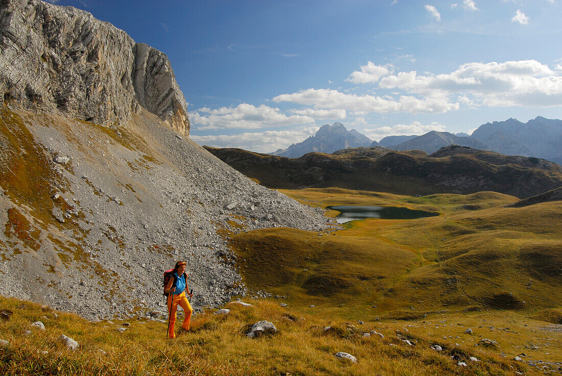 Junge Frau im Aufstieg zum Fossesriedel mit Blick auf Großen Fossessee und Tofana im Hintergrund, Dolomiten-Höhenweg Nr. 1, Naturpark Fanes-Sennes, Dolomiten, Südtirol, Alta Badia, Italien