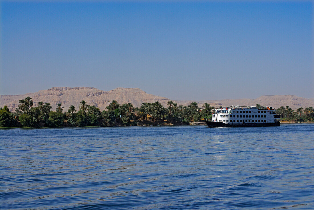 Kreuzfahrtschiff auf dem Nil und Palmen am Westufer, Luxor, Ägypten, Afrika