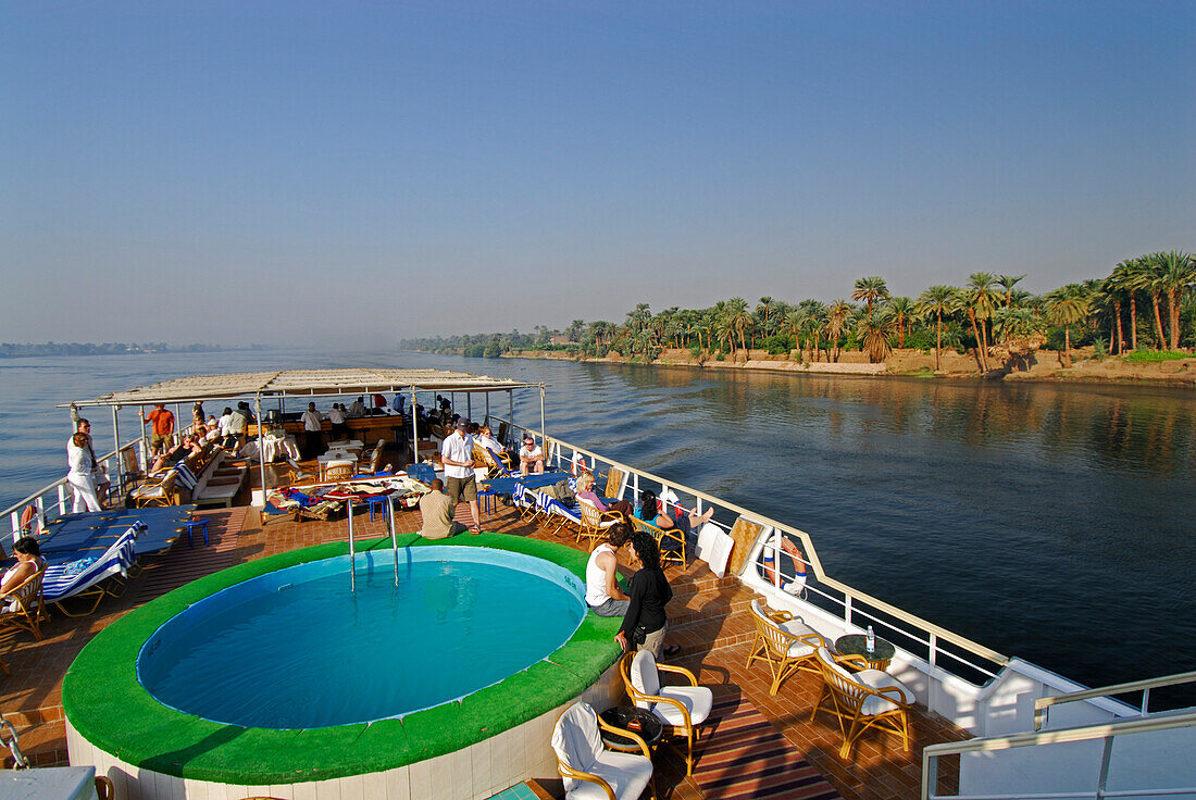 cruise on the Nile, view from upper deck to pool on deck and palm trees at western bank, Nile between Luxor and Dendera, Egypt, Africa