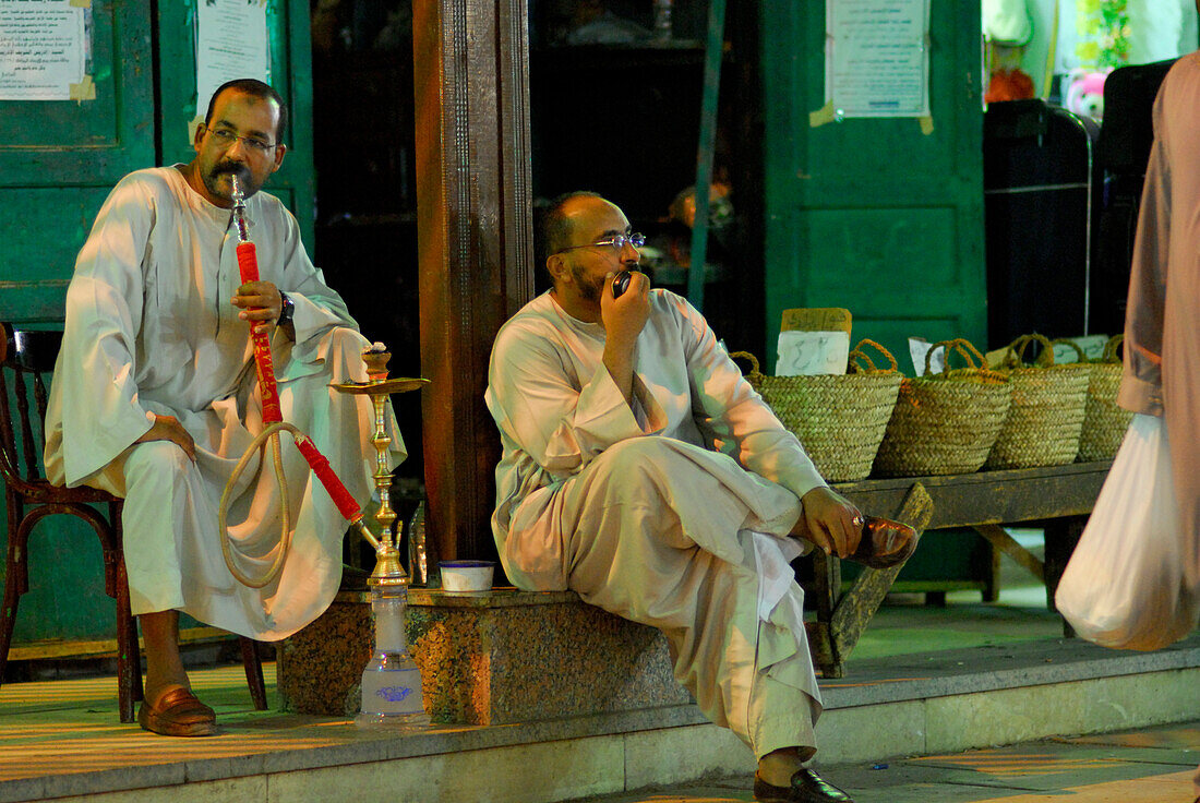 two men, one smoking water pipe (hookah), street scene at night, market in Aswan, Egypt, Africa