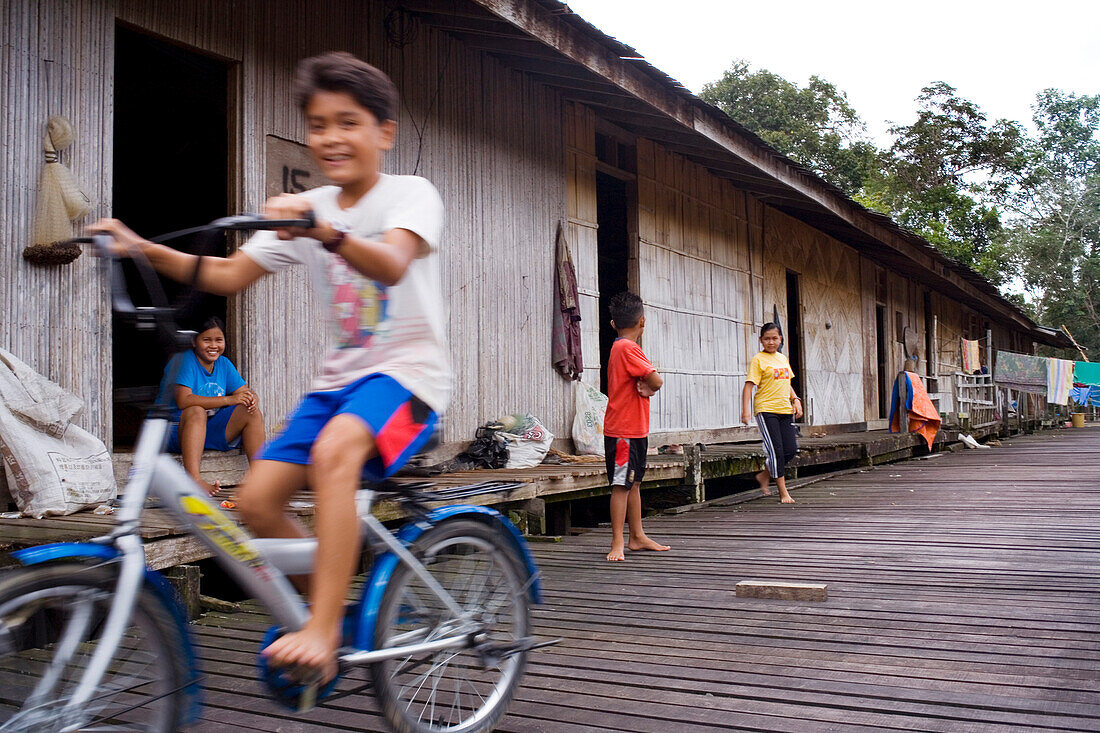 Kinder spielen vor Langhaus der Iban, Kuching, Sarawak, Borneo, Malaysia