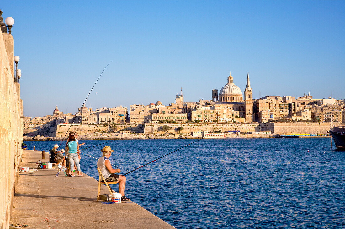 Angler auf der Uferpromenade im Sonnenlicht, Blick auf die Stadt Valletta, Marsamxett Hafen, Sliema, Malta, Europa