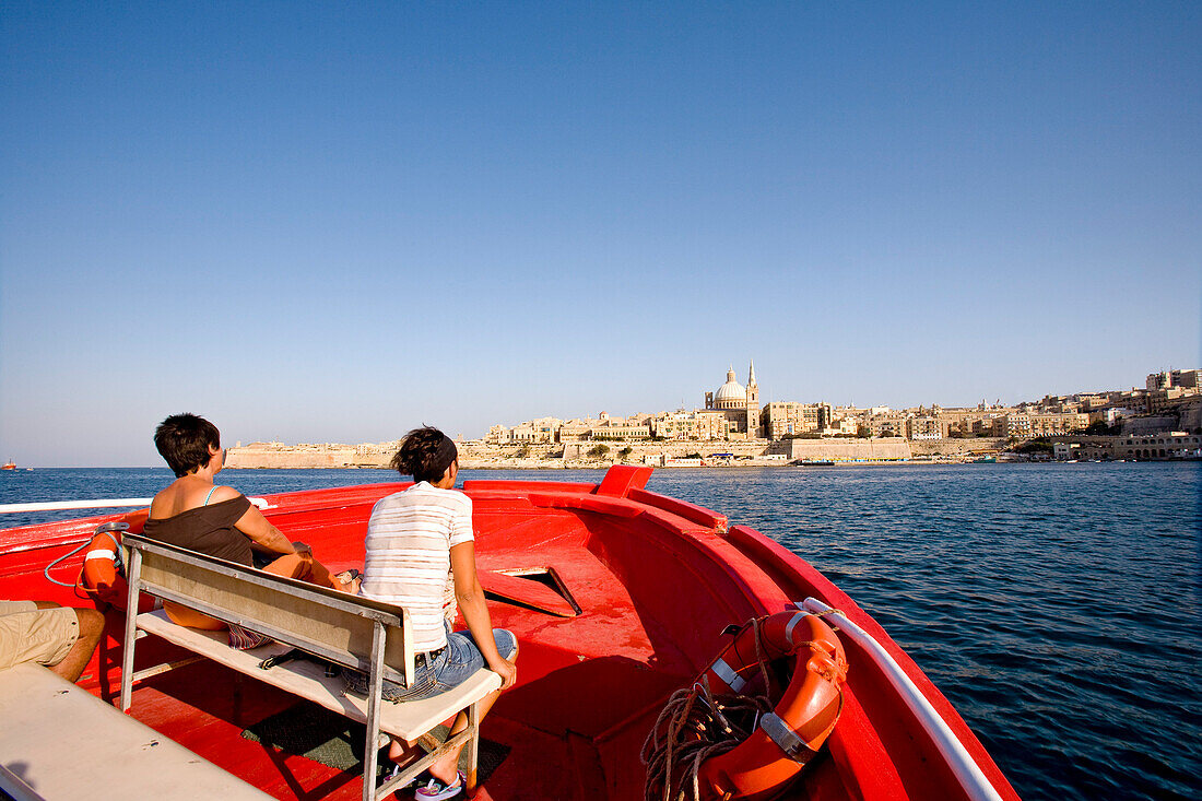 Menschen im Boot unter blauem Himmel, Blick auf die Stadt Valletta, Malta, Europa