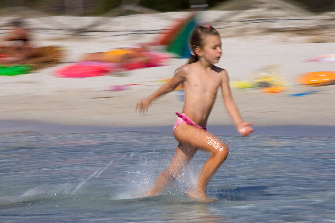 Kleines Mädchen läuft am Strand, Sardinien, Italien