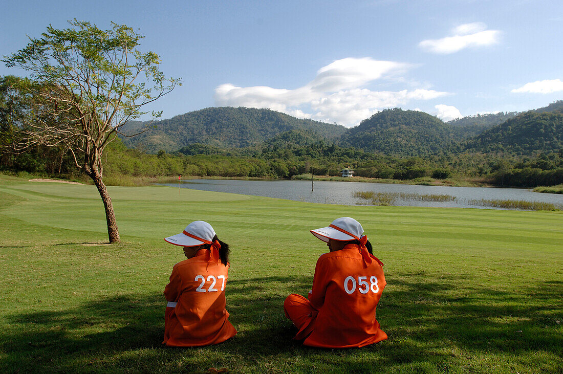 Two women sitting on the grass, caddy, Kirimaya Golf Course, Khao Yai National Park, Thailand