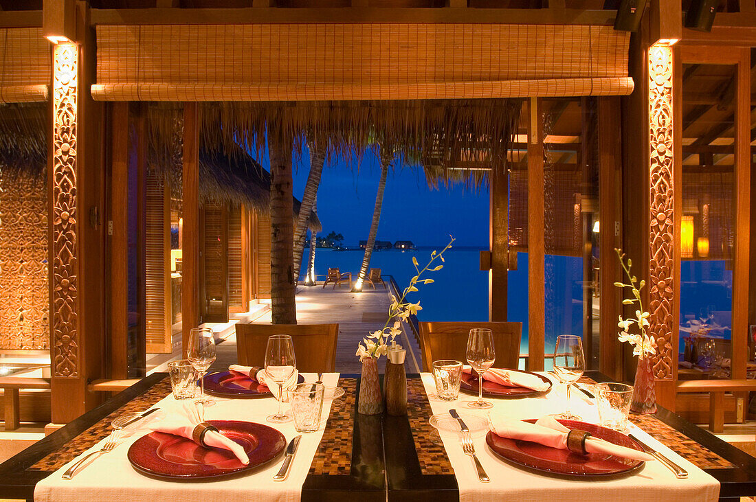 A set table inside Reethi Restaurant at night, One & Only Resort Reethi Rah, Maldives