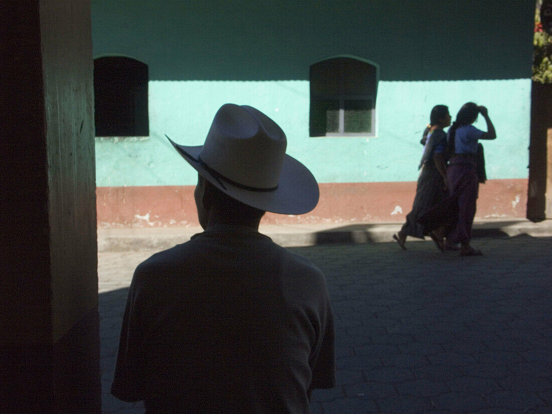 A man waits in the shade to escape the mid day heat on streets of San Lucas Toliman, Guatemala, near Lake Atitlan