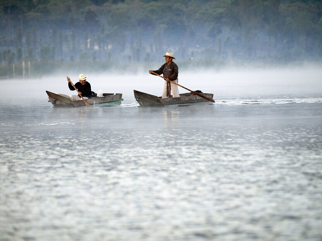 Fishermen at work on Lake Atitlan, which is a lake surrounded by three volcanoes in Santiago Atitlan, in the highlands of Guatemala, in Santiago Atitlan, Guatemala.