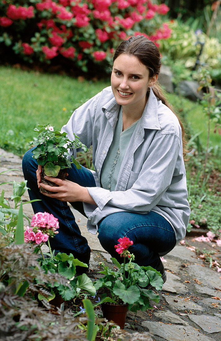 rs, 30-40 years, Adult, Adults, Color, Colour, Contemporary, Crouch, Crouching, Daytime, Exterior, Facing camera, Female, Full-body, Full-length, Garden, Gardening, Gardens, Generation X, Grin, Grinni