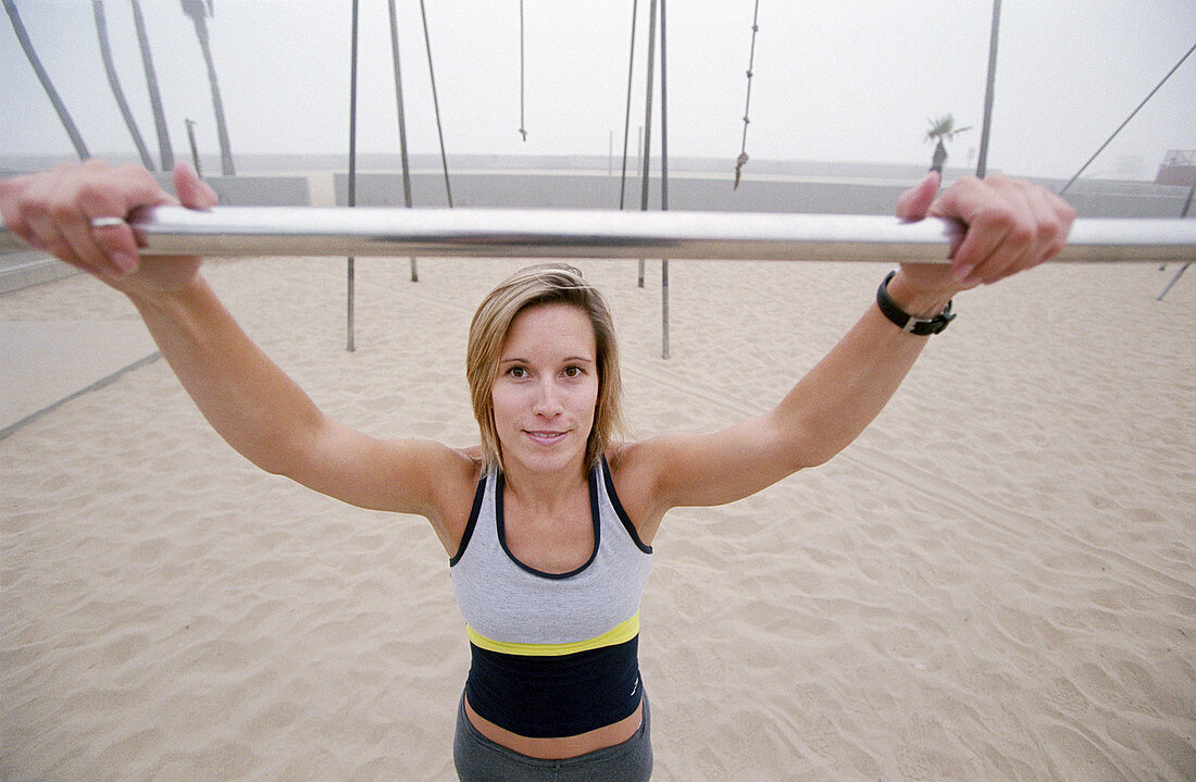 Woman in her mid 20 s doing pull ups. Venice. California. USA.