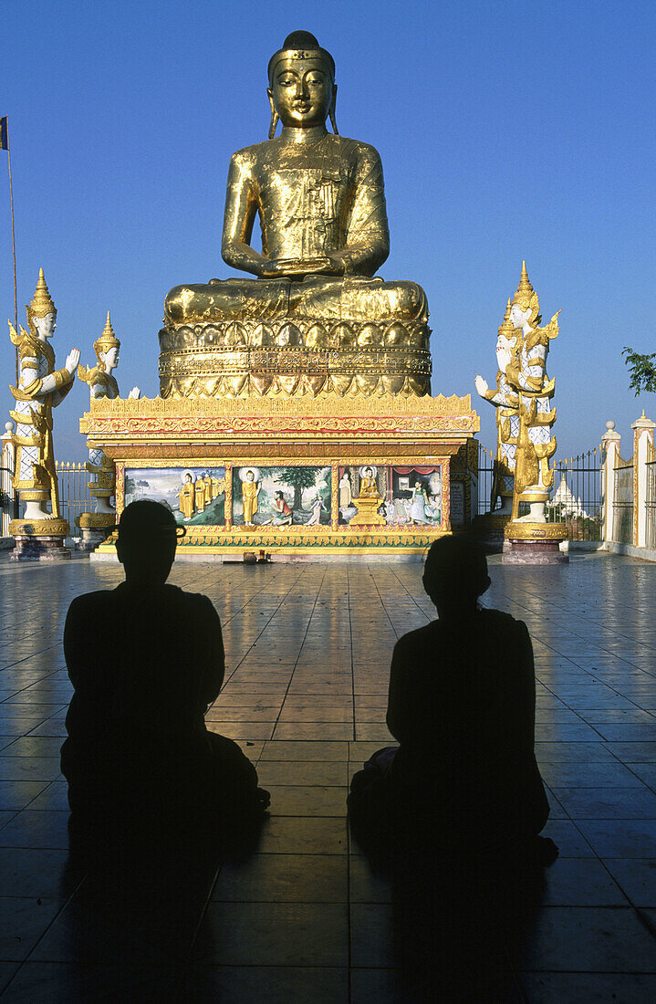 Women praying at Giant Buddha statue in temple. Saging. Mandalay. Myanmar (Burma).