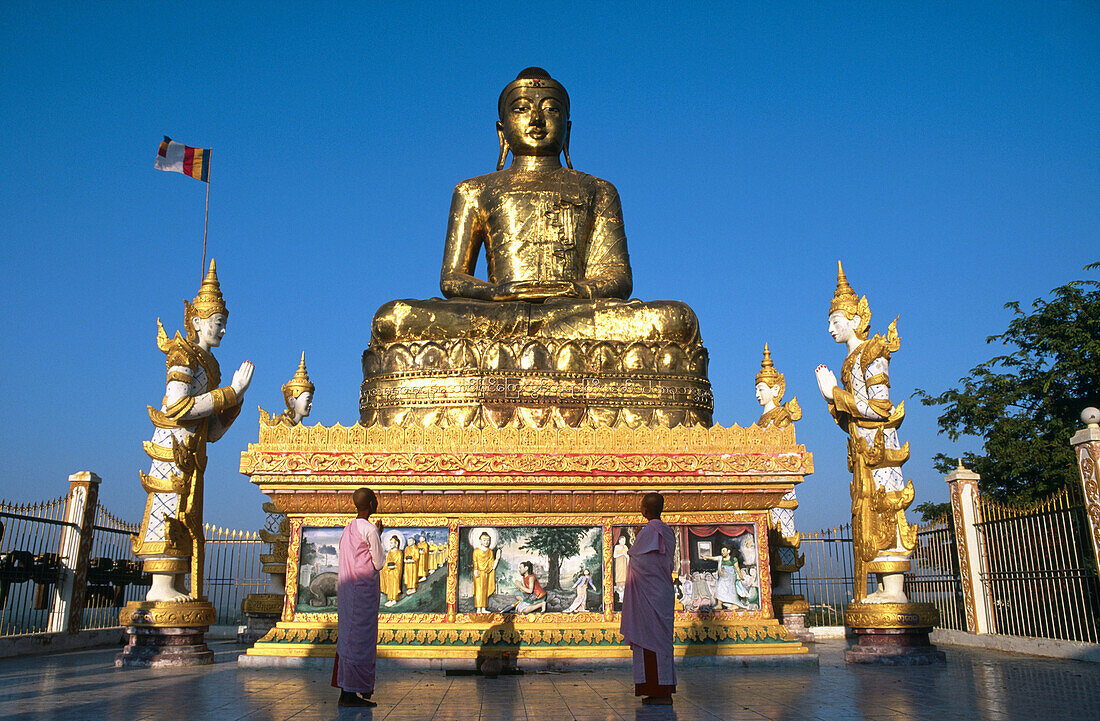 Buddhist nuns praying to Giant Buddha. Sagaing. Mandalay. Myanmar (Burma).