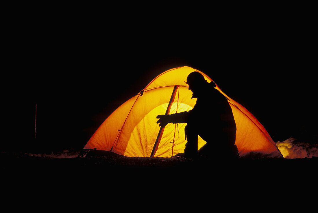 Person with headlamp silhouetted against a yellow dome tent at night. Sequoia National Park. California. USA