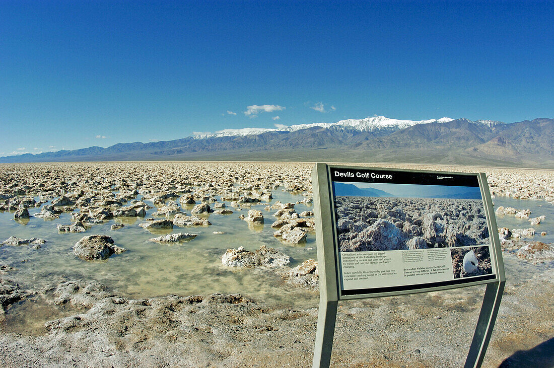Interpretative sign on the flooded salt pan at Devil s Golf Course under Telescope Peak, Death Valley National Park, California