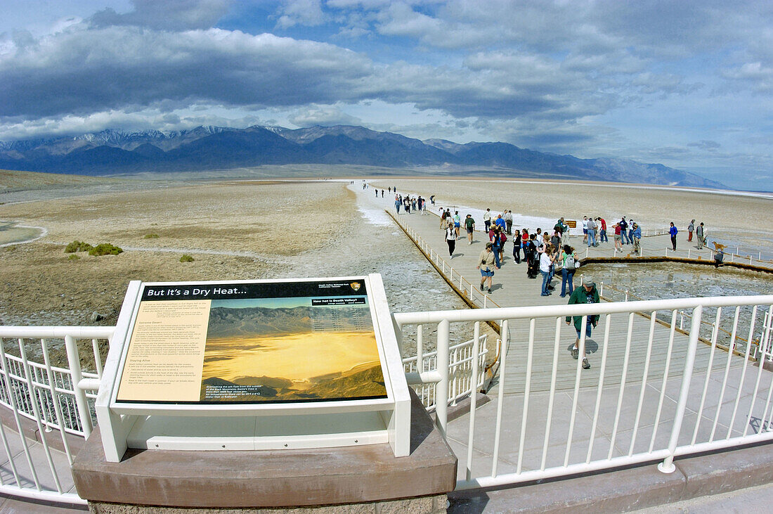 Interpretative sign and tourists on the boardwalk at Badwater (lowest point in the US) under Telescope Peak, Death Valley National Park, California