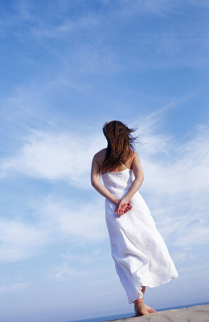  Adult, Adults, Alone, Back view, Blue, Blue sky, Calm, Calmness, Color, Colour, Contemporary, Daytime, Dress, Dresses, Exterior, Female, Freedom, Full-body, Full-length, Human, Long hair, Long haired, Long-haired, One, One person, Outdoor, Outdoors, Outs