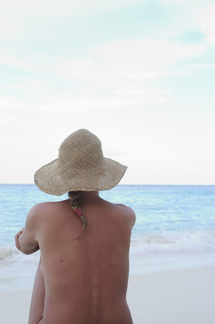  Adult, Adults, Alone, Back view, Bare, Beach, Beaches, Calm, Calmness, Chill out, Chilling out, Color, Colour, Contemporary, Daytime, Exterior, Female, Hat, Hats, Headgear, Holiday, Holidays, Horizon, Horizons, Human, Leisure, Medium-shot, Naked, Nude, N