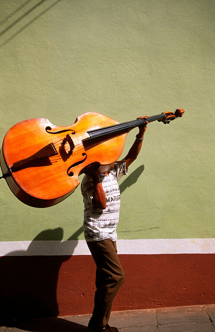 A bass player carrying his double bass. Trinidad de Cuba. Cuba