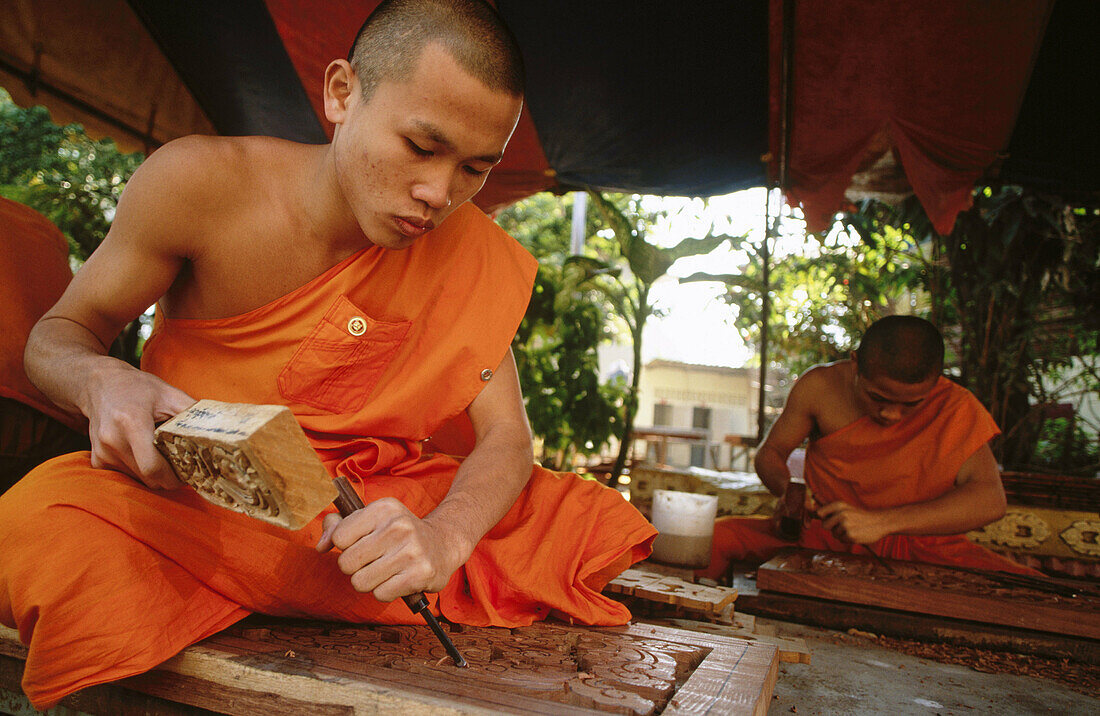 Monk carving wood in Buddhist temple. Vientiane, Laos