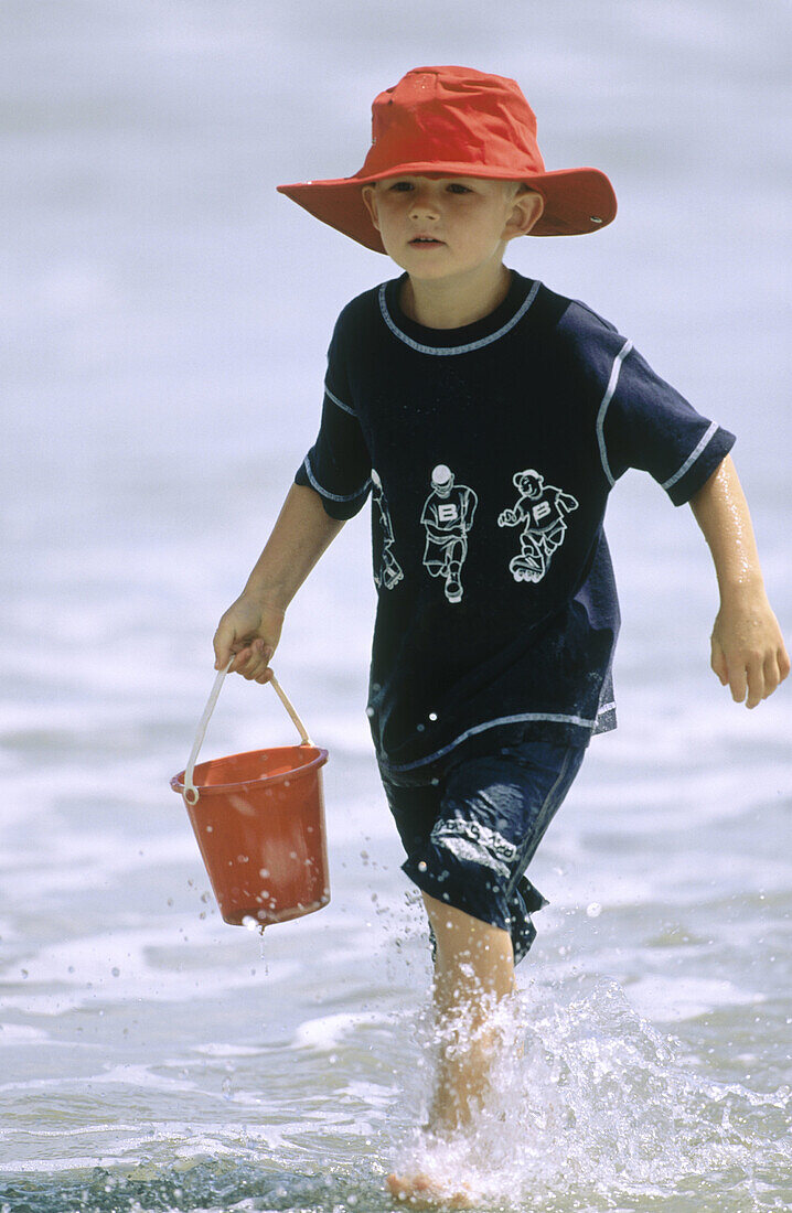 Young child covered up for the sun. Mt. Maunganui. New Zealand.