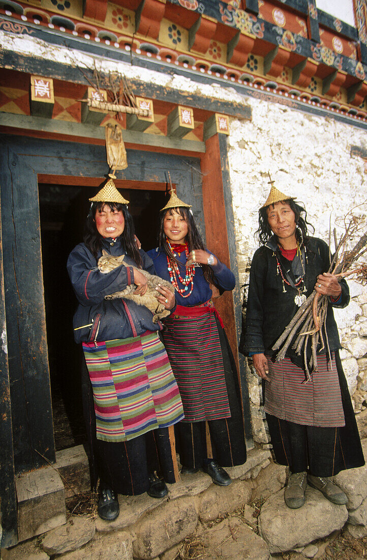Laya women in doorway. Traditional dress and conical bamboo hats. Laya. Bhutan