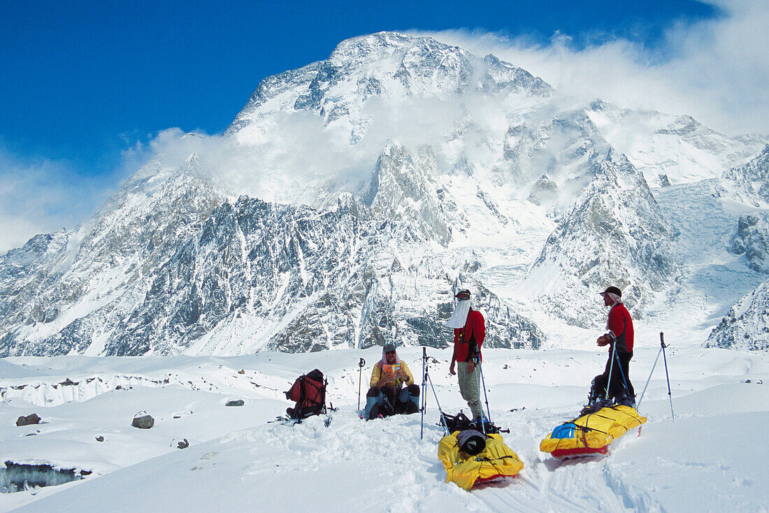 Skiers hauling sleds under Broad Peak, Godwin-Austen glacier. Karakoram mountains, Pakistan