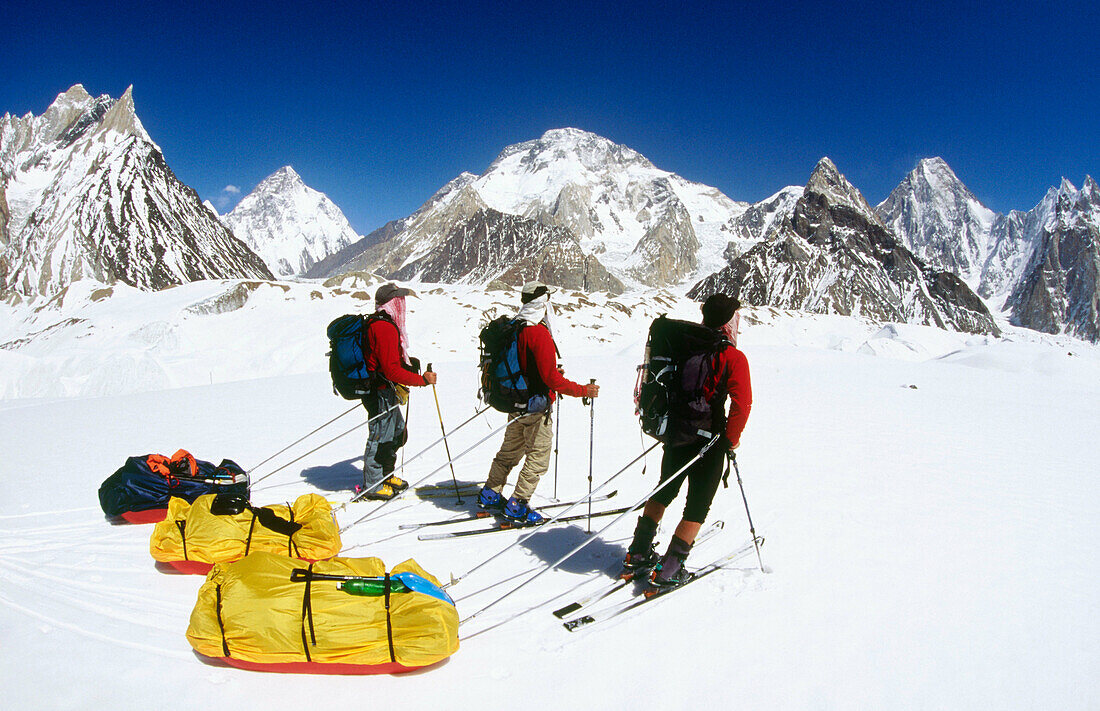 Skiers reach Concordia with K2 behind, Baltoro and Godwin-Austin Glaciers junction. Karakoram mountains, Pakistan