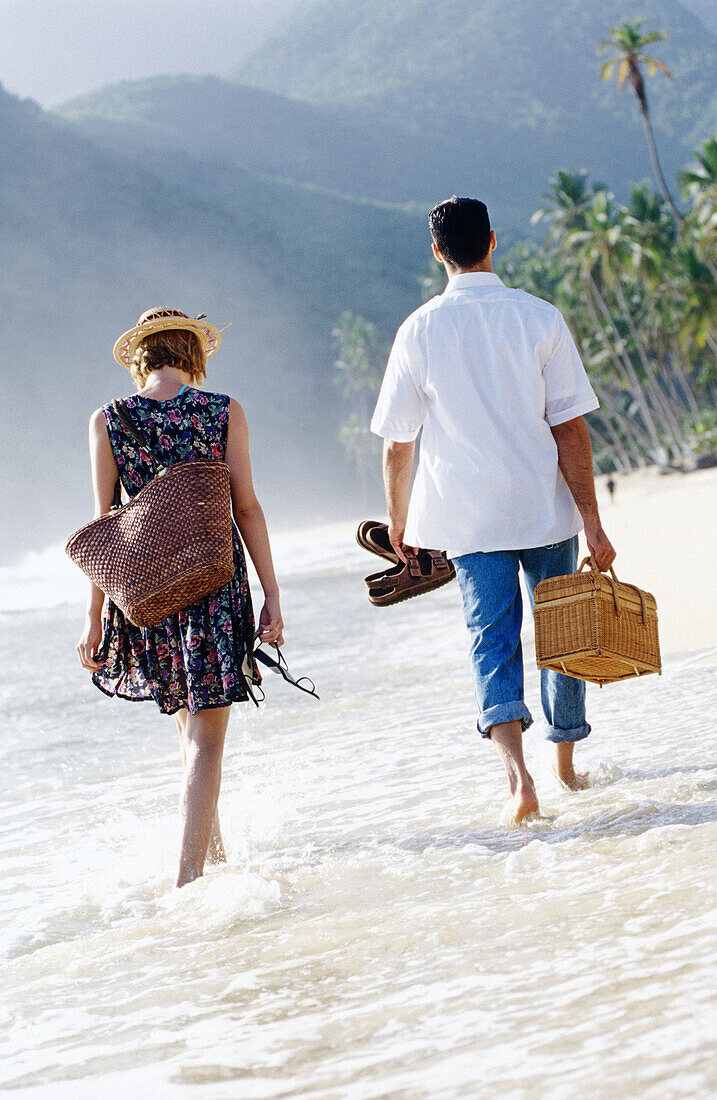 Couple walking on the beach with picnic basket