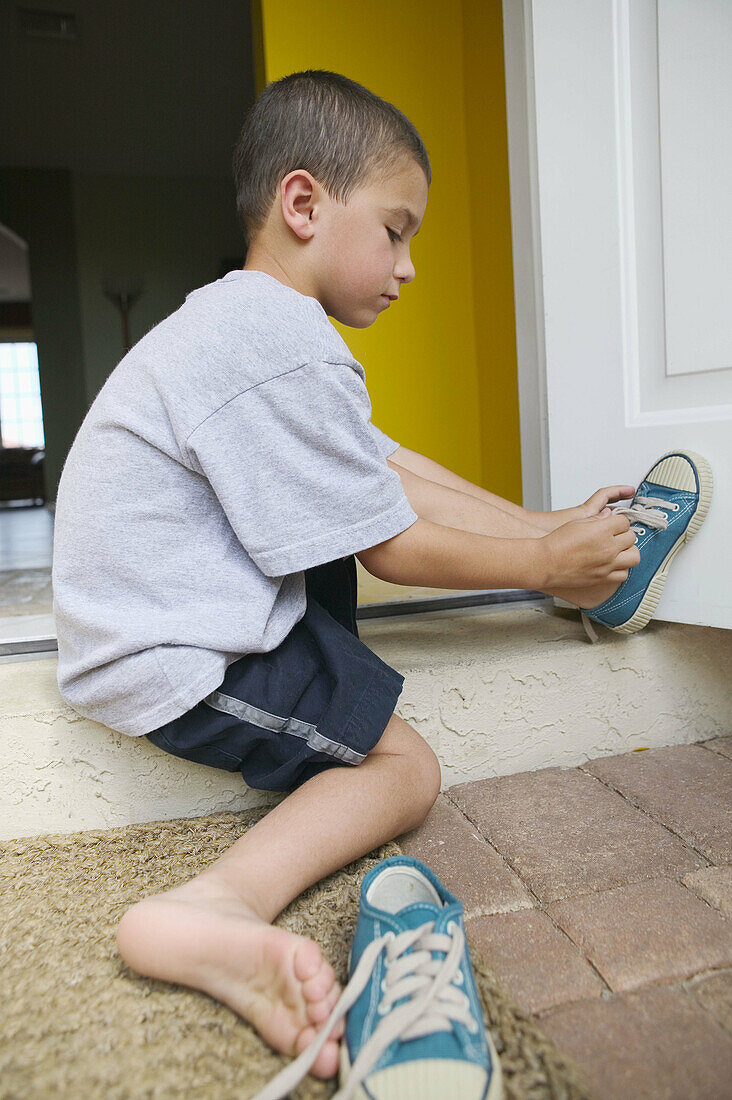 Boy putting on shoes outdoor