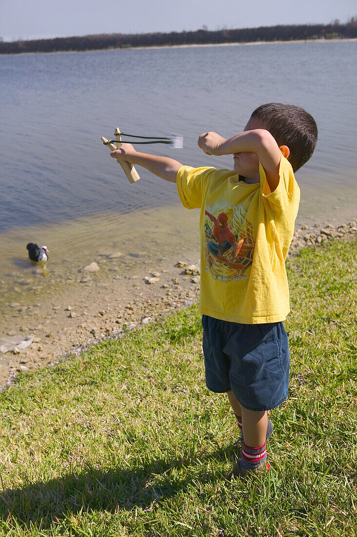 Boy with slingshot by the lake