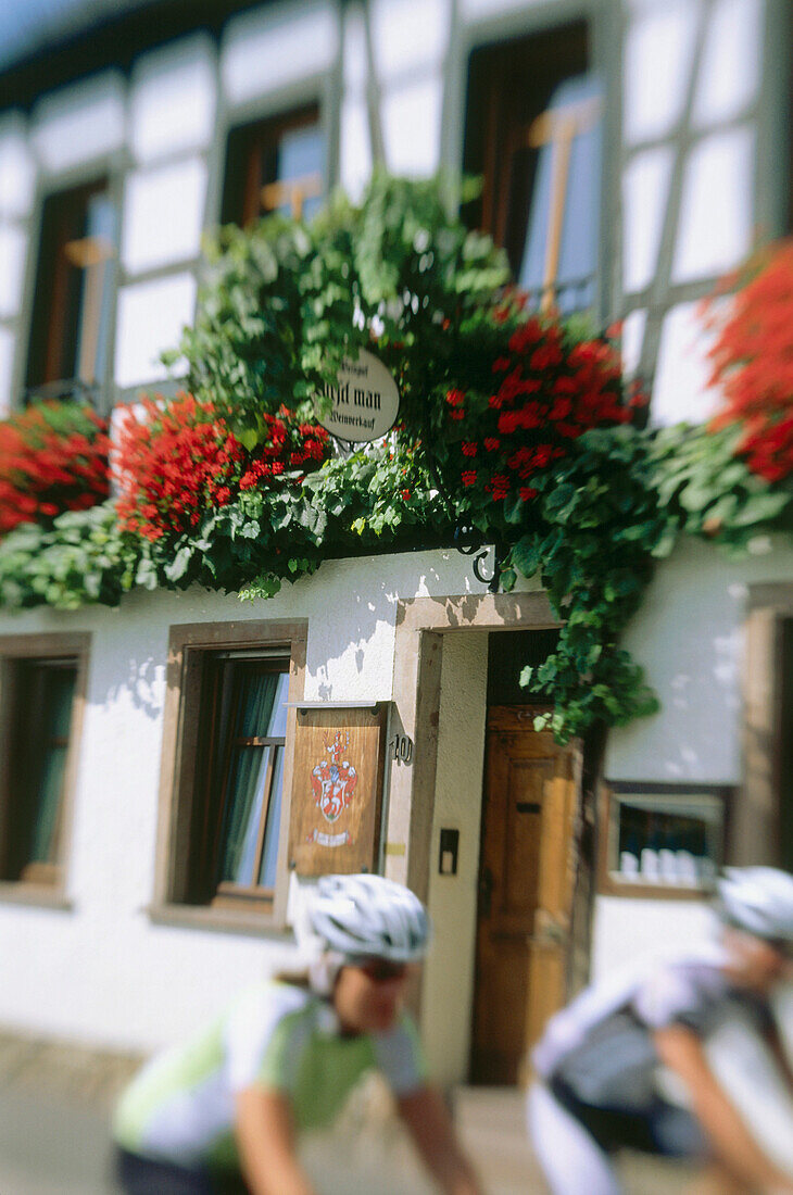Cyclists passing timbered house, Rhine District, Hesse, Germany