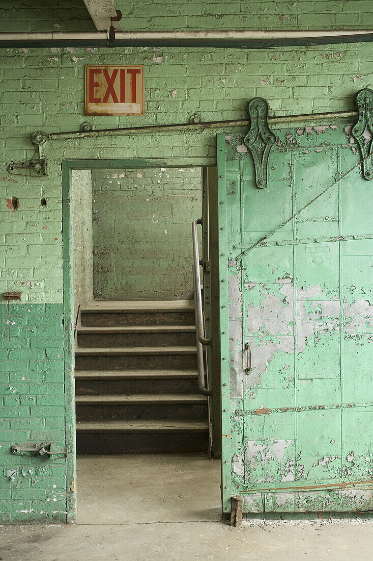 Green exit fire door, flaking old paint, Gilbert & Bennett wire mill, Georgetown, Connecticut. USA.