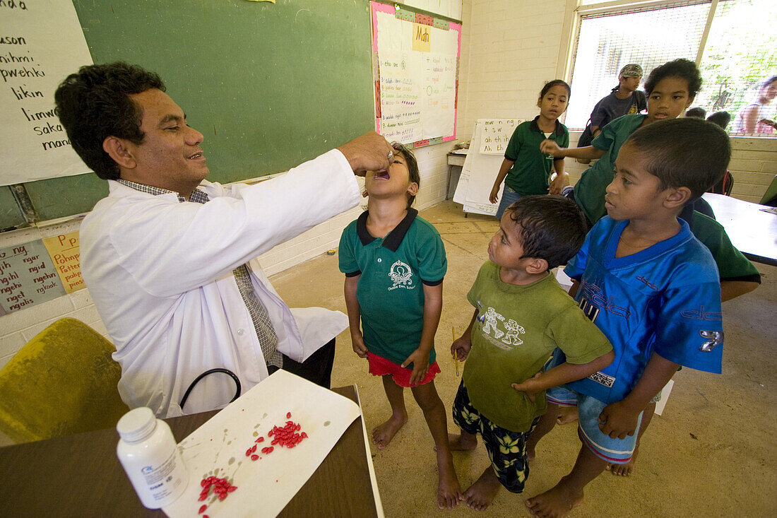 Doctor giving vitamins to pupils at school, Pohnpei, Micronesia, Oceania