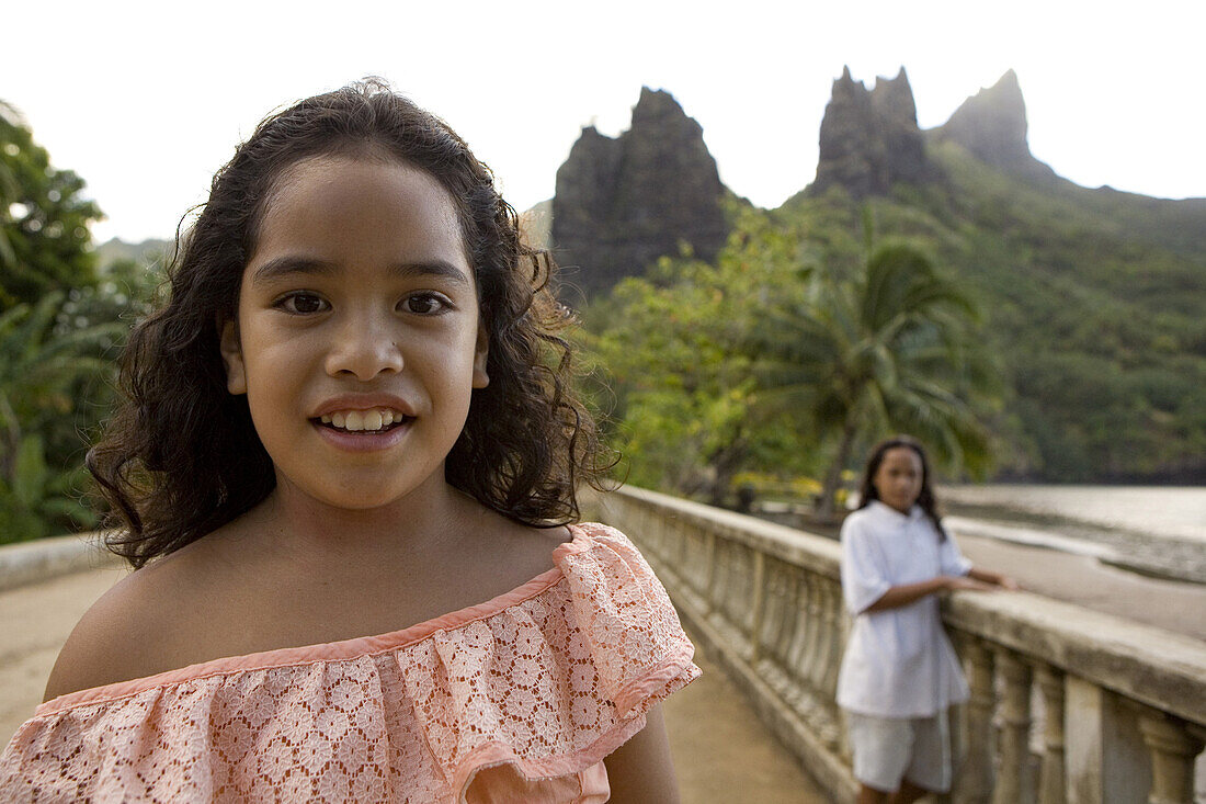 Zwei Mädchen vor Bergspitzen von Hatiheu, Nuku Hiva, Marquesas, Polynesien, Ozeanien