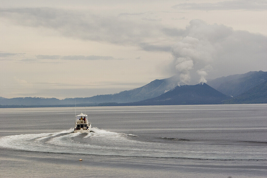 Boat in front of smoking volcano, Rabaul, New Britain, Papua New Guinea